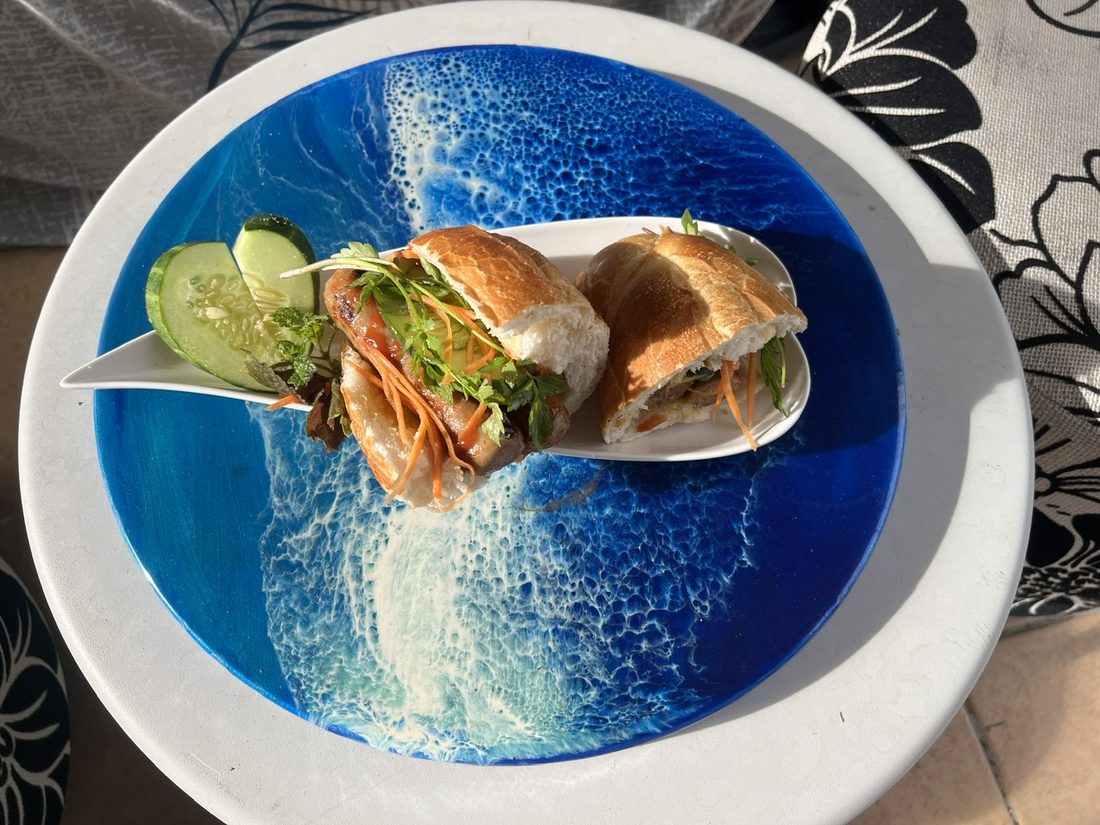 Grilled pork banh mi with fresh herbs and pickled carrot, served on a blue ocean-pattern plate